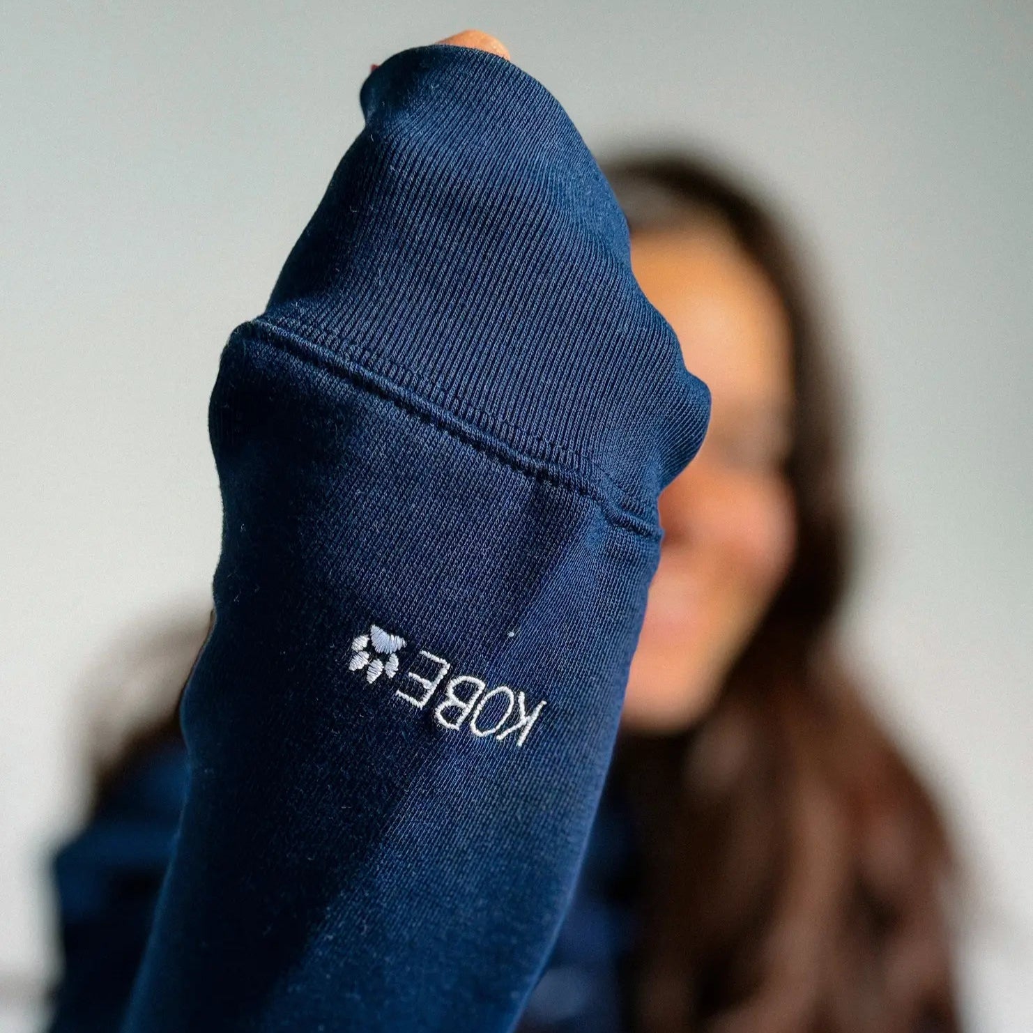 Navy sock with a brand logo held by a person against a neutral background