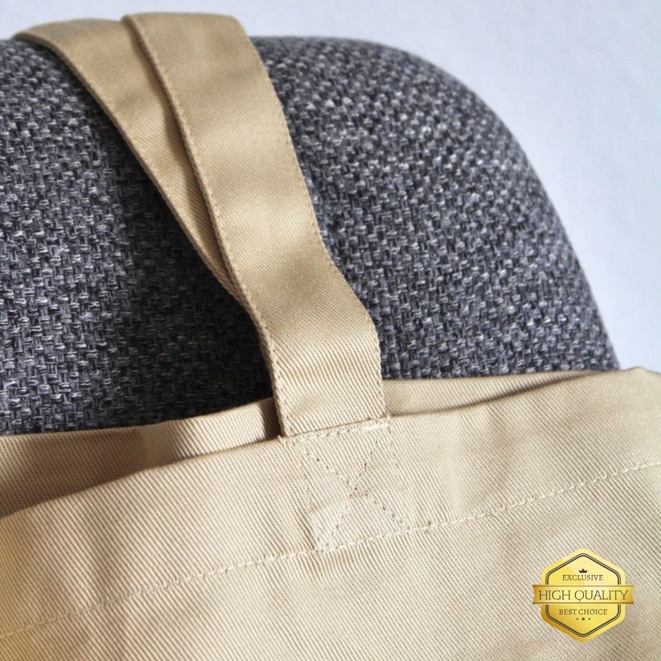 Close-up of a gray textured bag with beige strap and corner, featuring a high-quality badge.