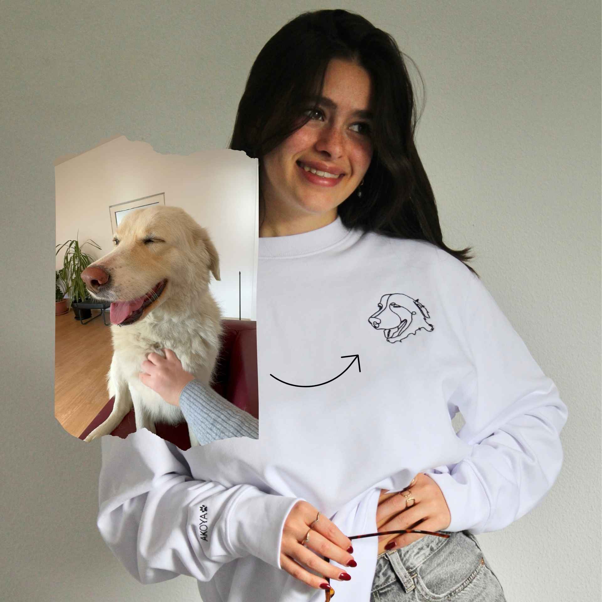 Woman wearing a white sweatshirt with a dog design, holding a dog.