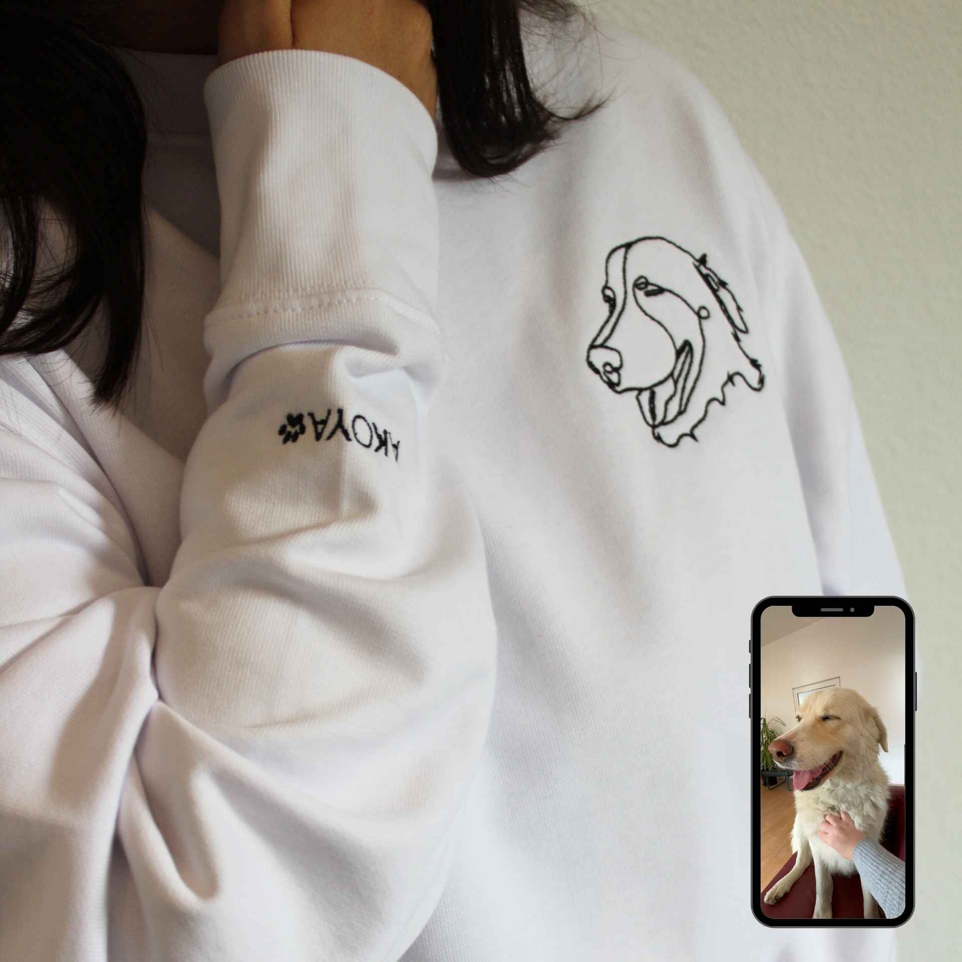 Person wearing a white sweatshirt with a horse design and 'KOKYA' branding, holding a phone with a dog photo.
