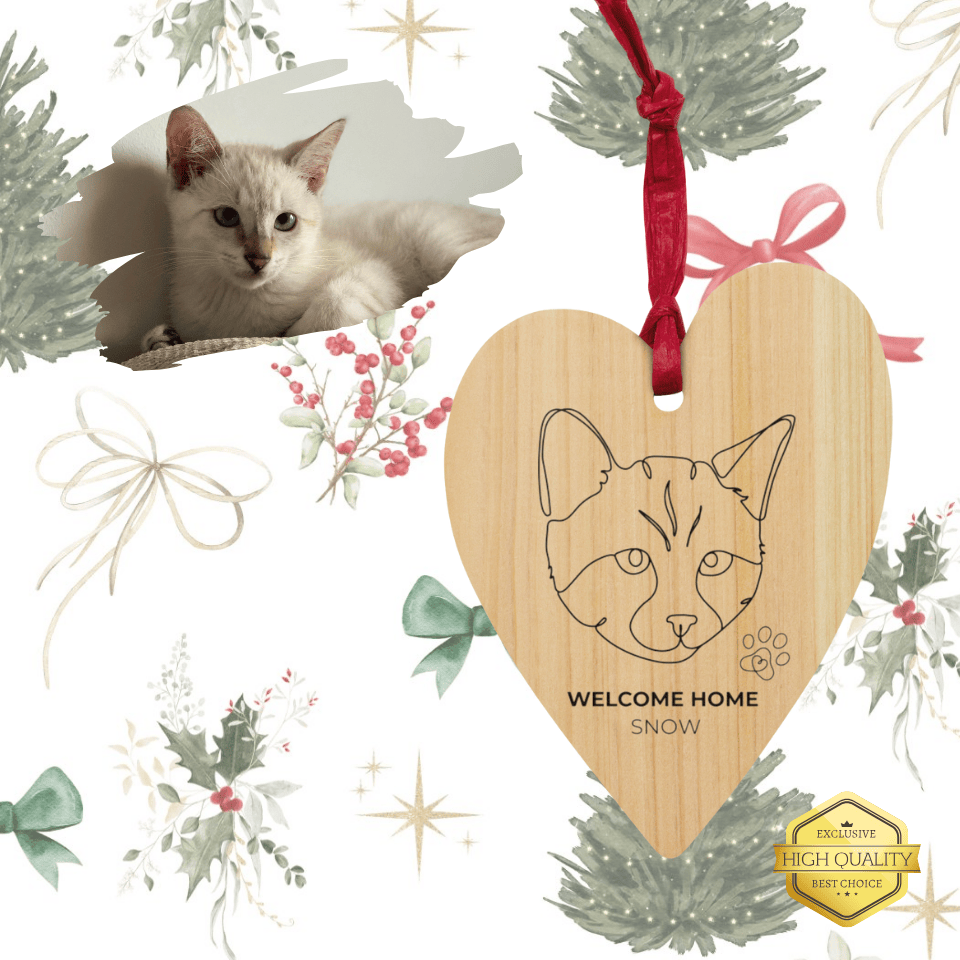 Heart-shaped wooden ornament with a cat design and text, surrounded by festive decorations.