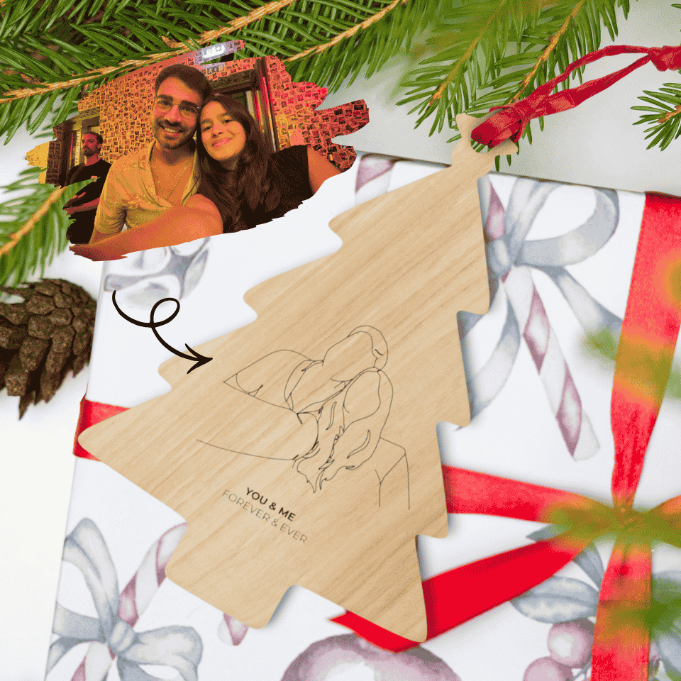 Wooden ornament with a couple's photo and 'You & Me Forever Love' text, surrounded by Christmas decorations.