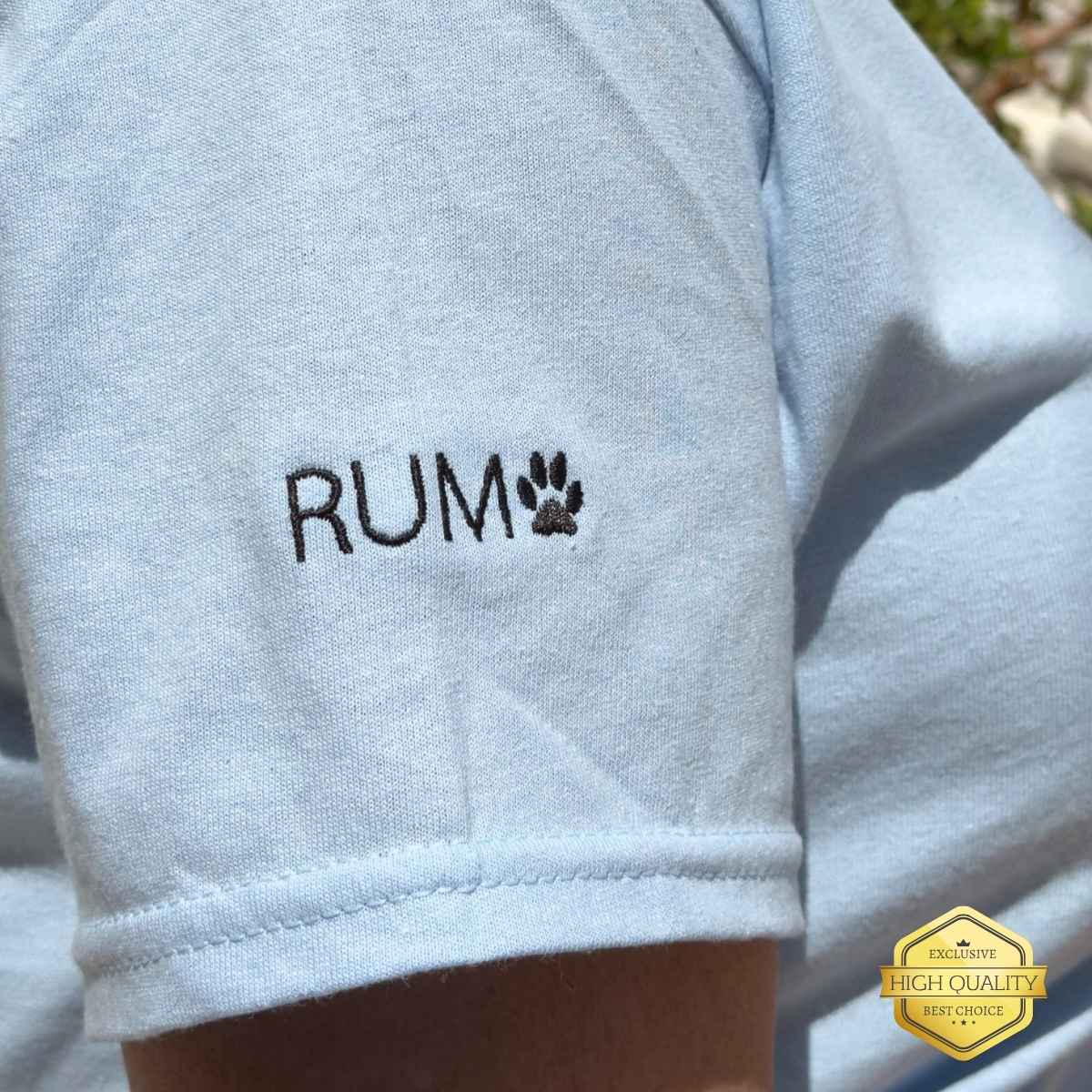 Light blue sleeve with 'RUM' embroidery on a person wearing a light blue shirt outdoors.