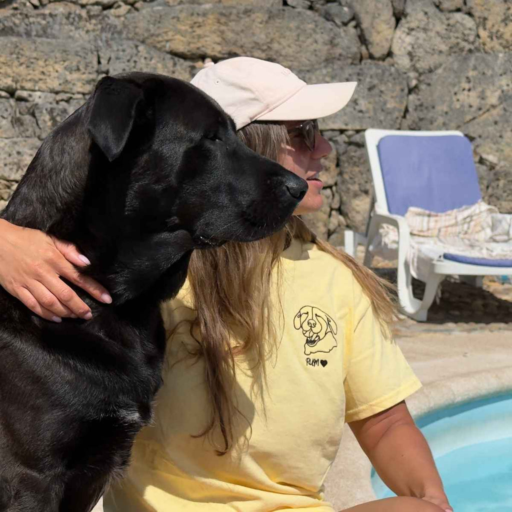 Person in a yellow shirt with a black dog by a pool